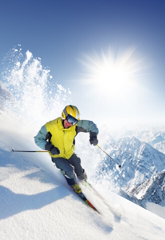 skieur professionnel dévalant une piste de ski ensoleillée